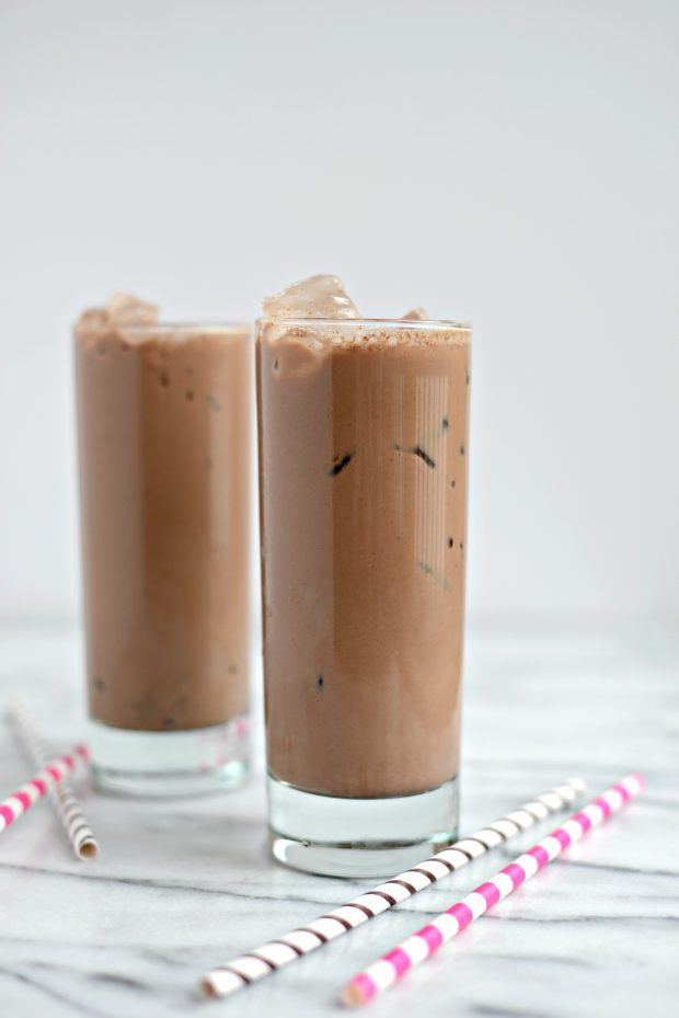 two glasses filled with chocolate milkshakes on top of a white table next to candy canes