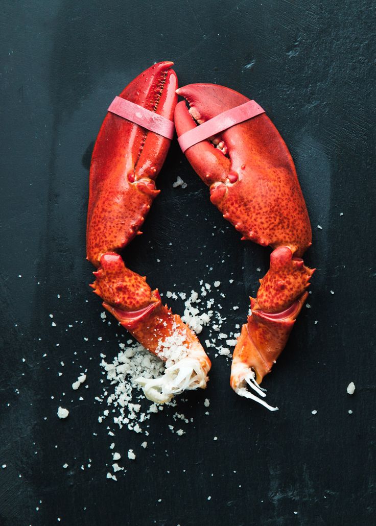 two lobsters on a black surface covered in sea salt and other things to eat