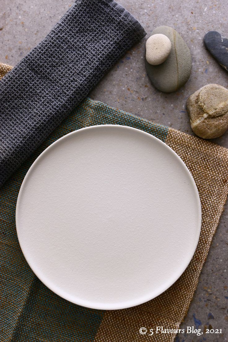 a white plate sitting on top of a table next to some rocks and a towel