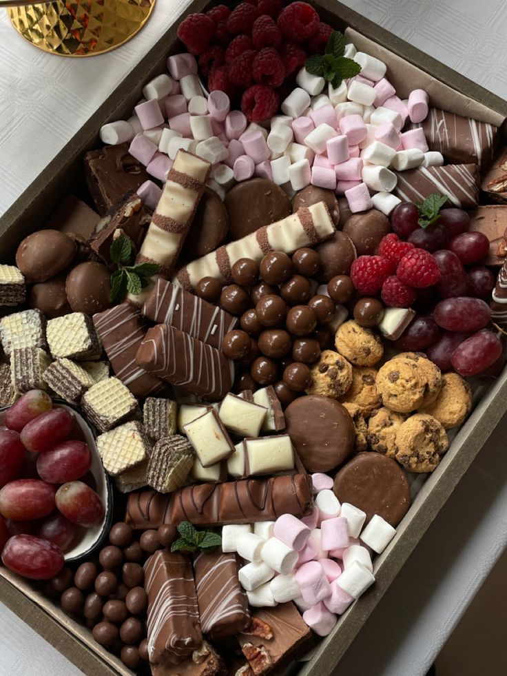 a box filled with lots of different types of chocolates and fruit on top of a table