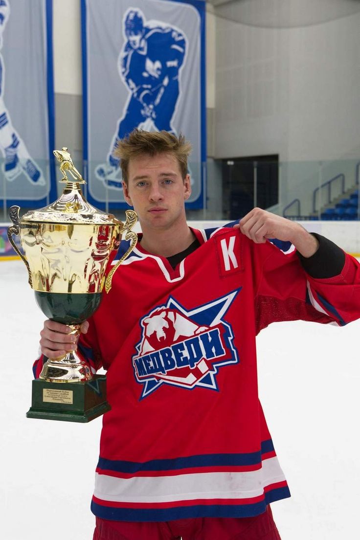 a young man holding up a trophy in front of an ice rink