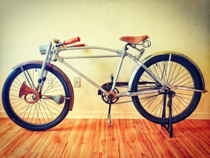 an old bicycle is sitting on the floor in front of a wall with wood floors