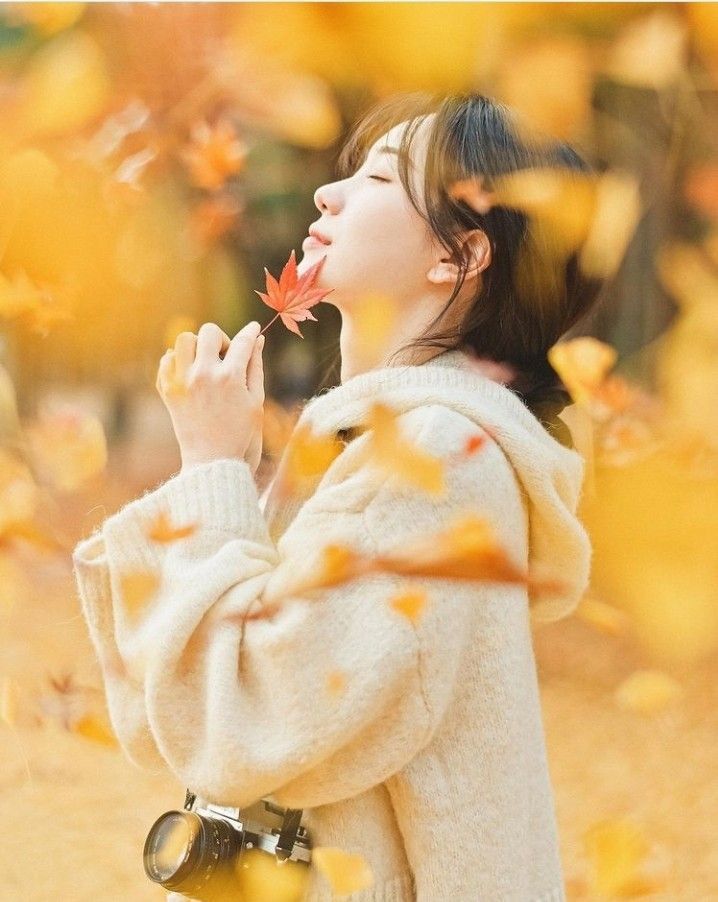 a young woman is blowing leaves in the air