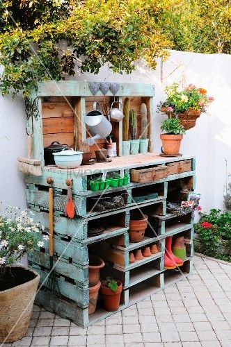 an outdoor garden with potted plants and gardening tools on top of a wooden bench