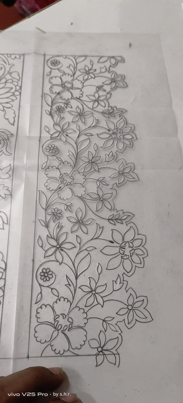 a person is cutting out some paper with flowers on it and the other side has been cut