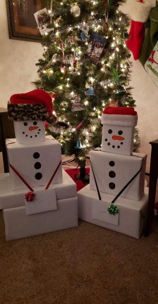 two snowmen made out of boxes sitting in front of a christmas tree