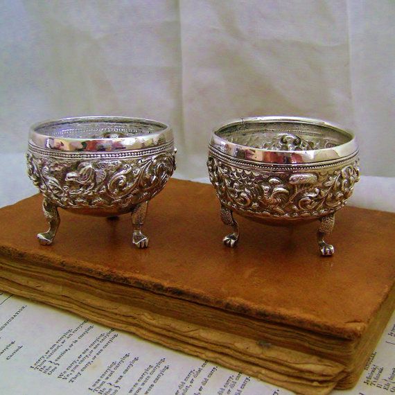 two silver bowls sitting on top of an old book