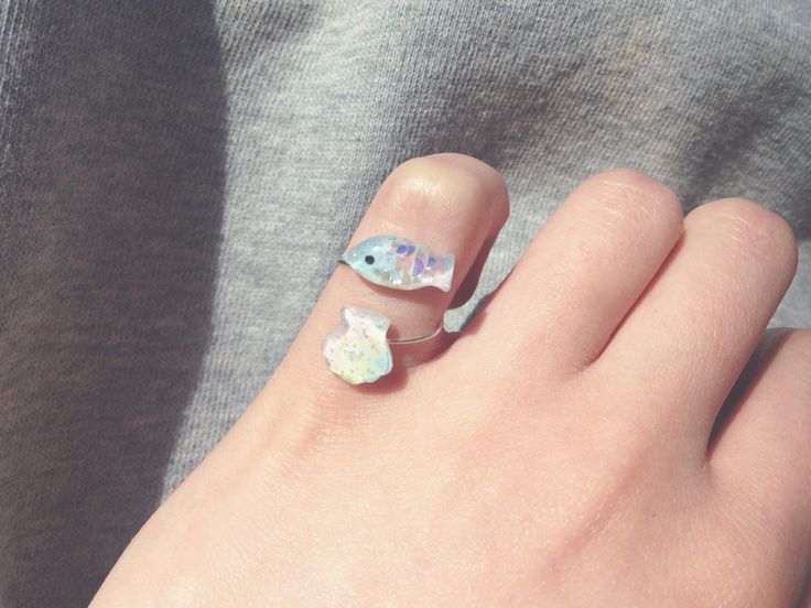 a person's hand with some nail polish on it and a ring in the middle