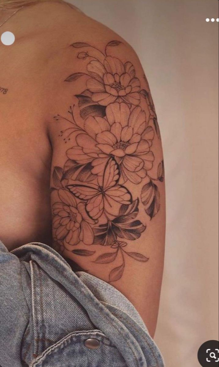 a woman's shoulder with flowers and leaves on the back of her left arm