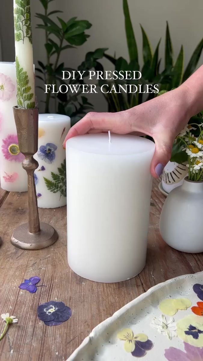 a person lighting a candle on a table with flowers in vases and plates around it