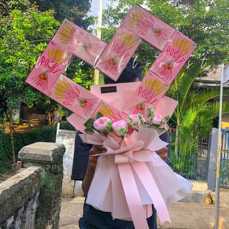 a man is walking down the street with flowers in front of him and some cards attached to his back