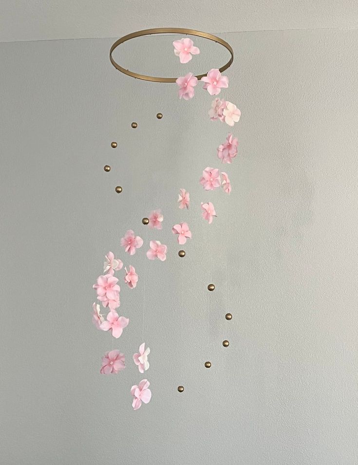 a mobile with pink flowers hanging from it's side on a wall in a room