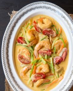 a white bowl filled with shrimp and vegetables on top of a cloth covered place mat