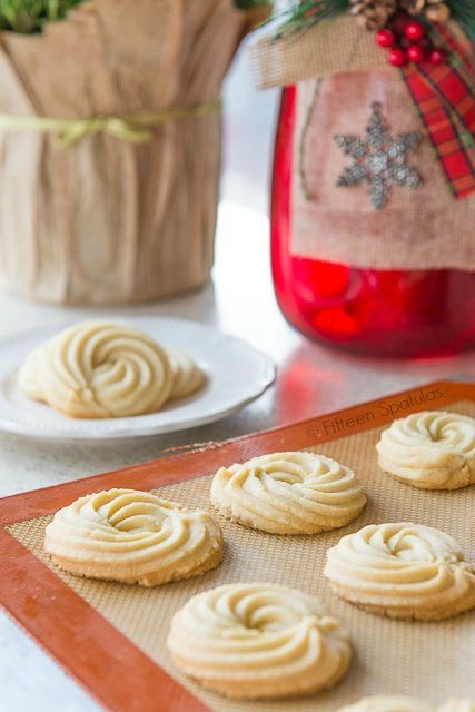 some cookies are sitting on a cookie sheet near a jar of christmas tree ornaments and a red mason jar