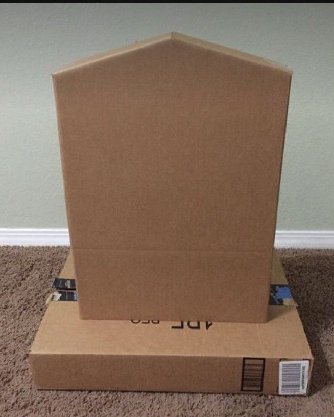 an open cardboard box sitting on top of a carpeted floor next to a wall