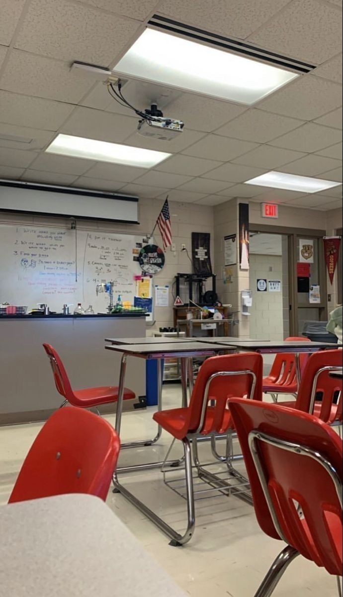 an empty classroom with red chairs and desks