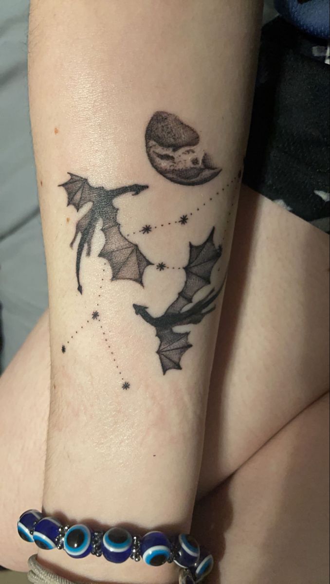 a woman's arm with a tattoo on it that has stars, planets and bats