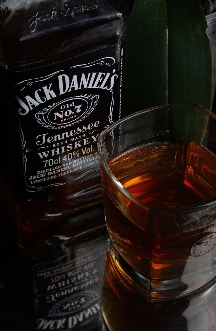 a glass filled with liquid sitting on top of a table next to a bottle of jack daniels