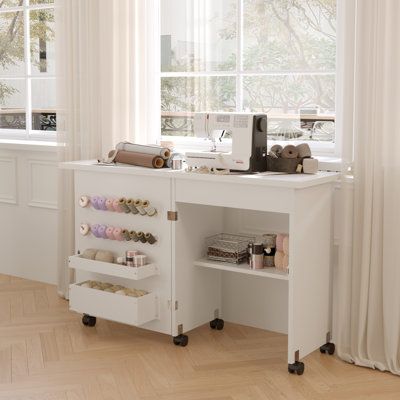 a sewing machine sitting on top of a white desk in front of a large window