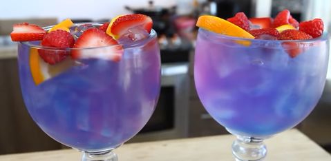 two glasses filled with blue liquid and fruit