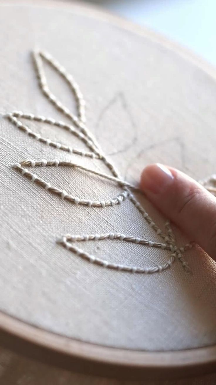 a hand is stitching on a piece of fabric