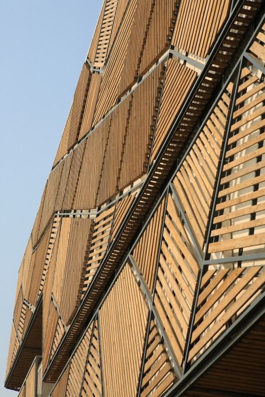 the side of a building with wooden slats on it's sides and a clock tower in the background