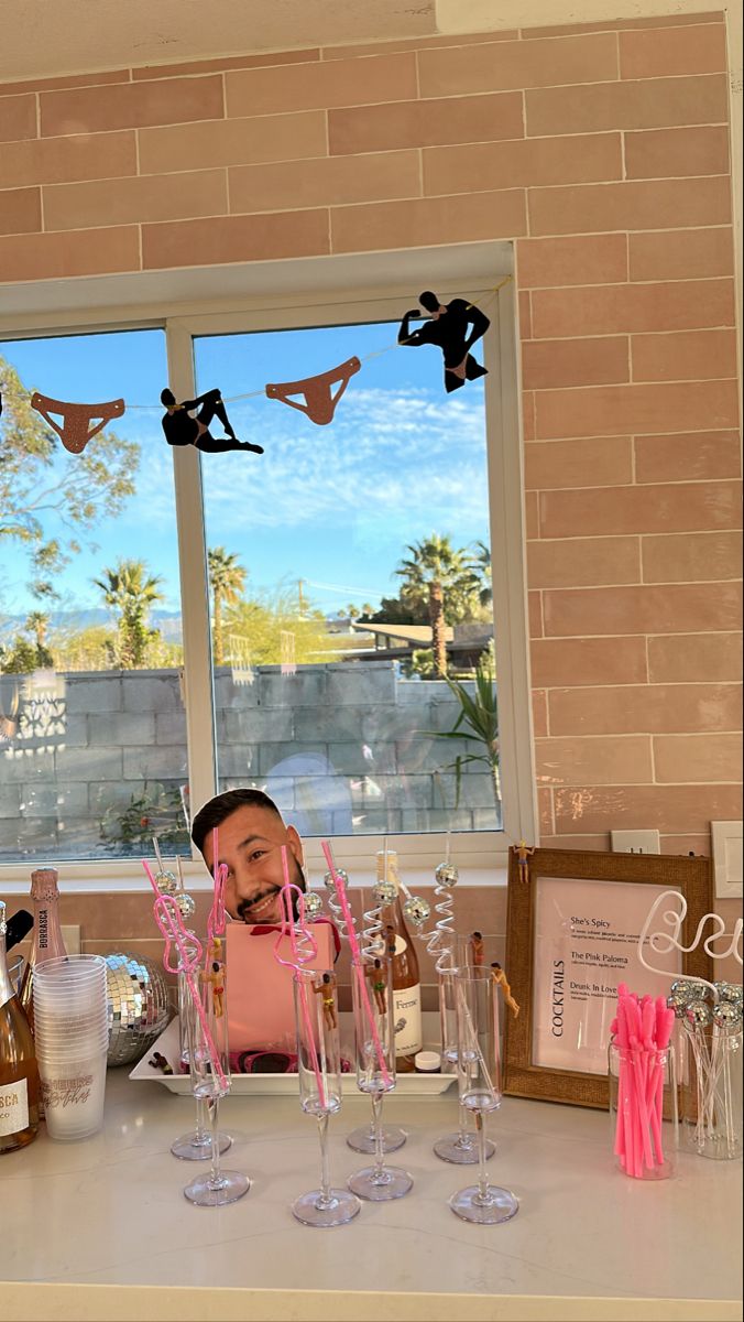 a man sitting at a table in front of wine glasses with pink straws on them