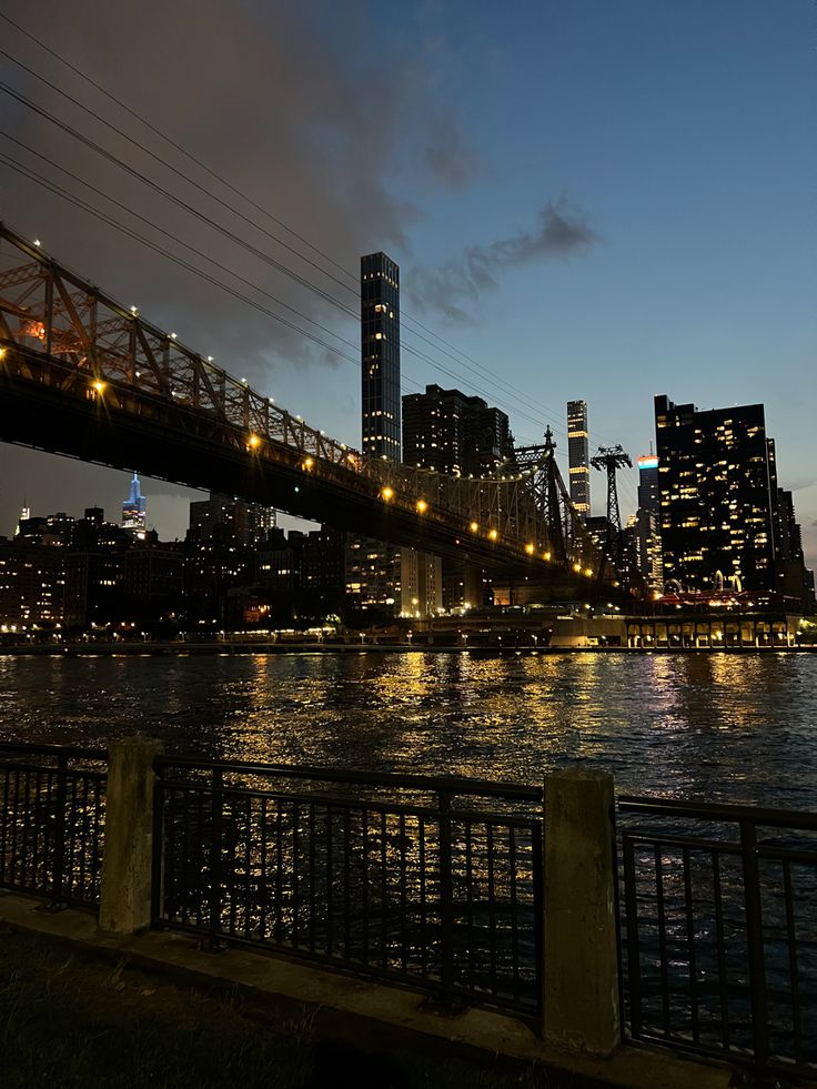 the city skyline is lit up at night with lights reflecting in the water below it