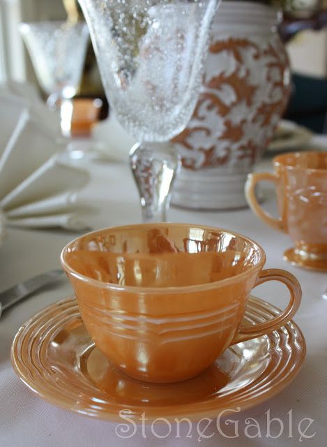 an orange glass cup and saucer on a table