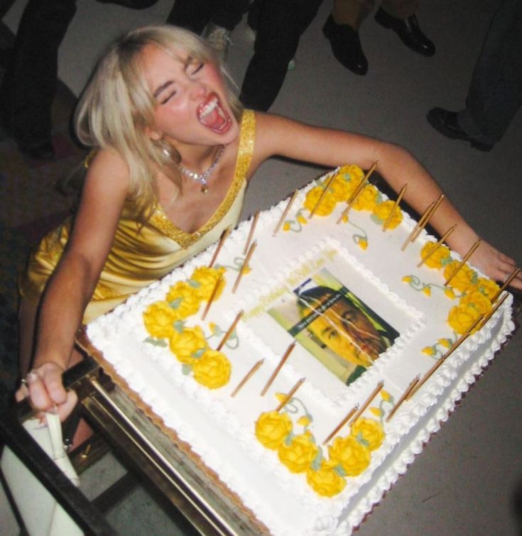 a woman in a yellow dress is holding a cake with candles on it and smiling