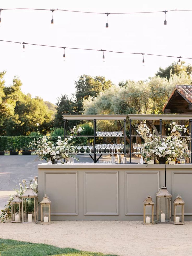 an outdoor bar set up with candles and flowers on the counter for a wedding reception