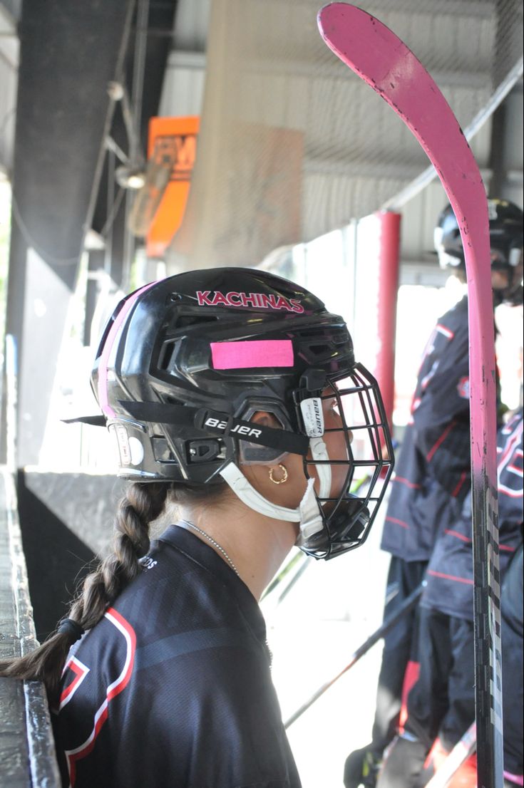 a girl wearing a catchers helmet and holding a baseball bat