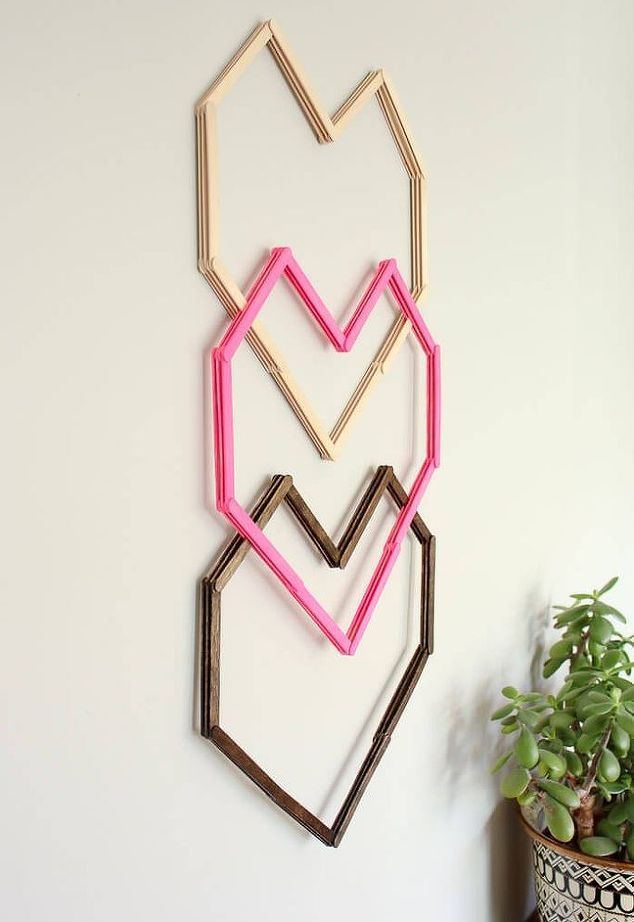 a wall hanging made out of wood sticks and some pink paint on the side of it