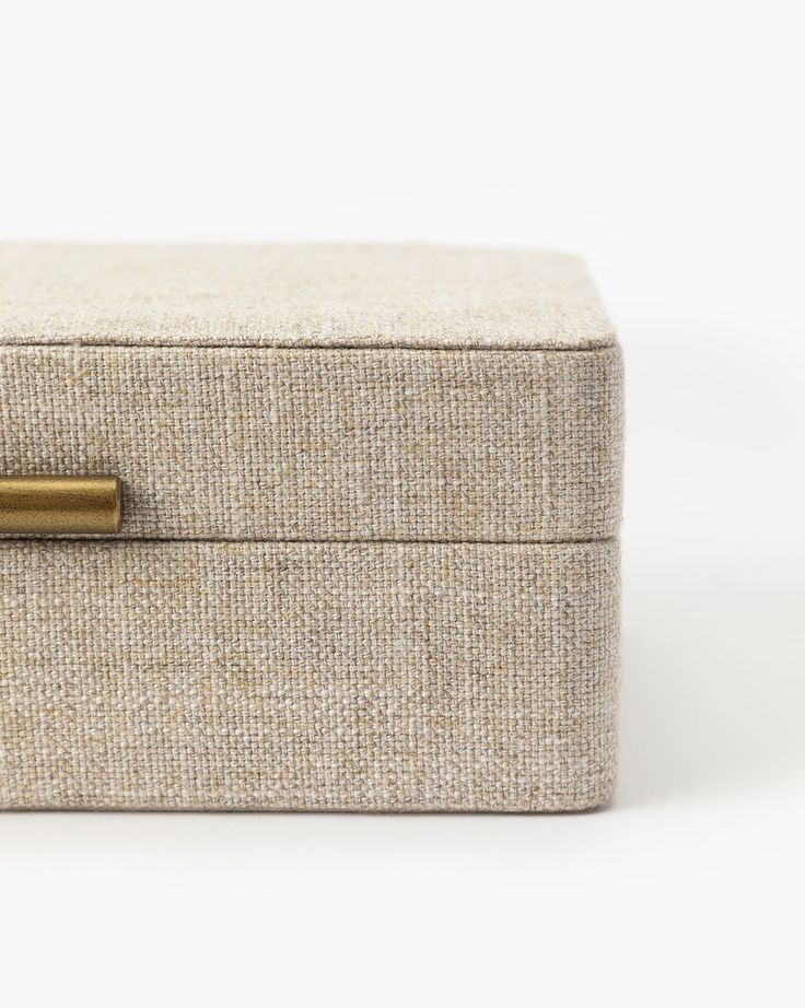 a beige box with a brass handle on it's side and the lid closed