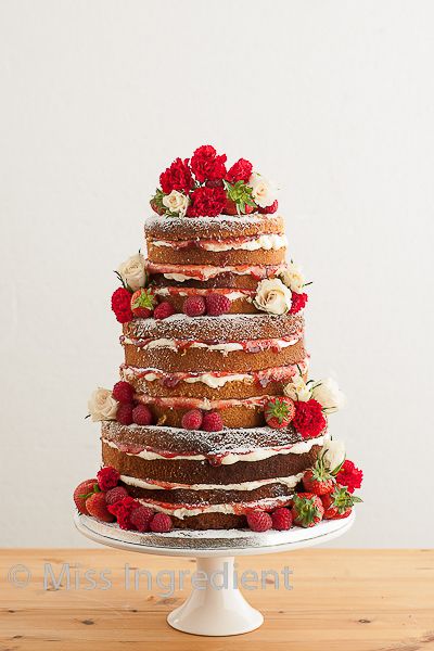 a multi layer cake with flowers and berries on top