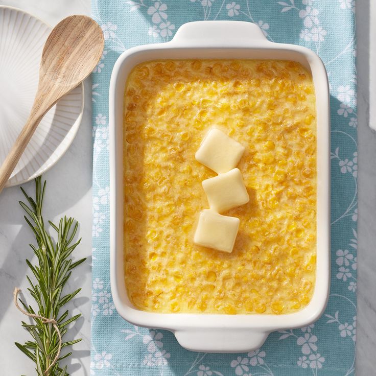 there is a dish with cheese in it and two spoons on the table next to it