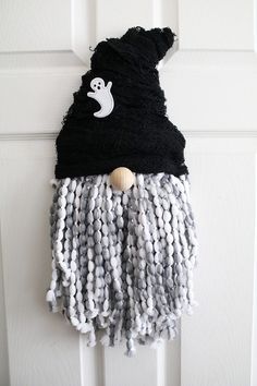 a door hanger with a black and white knitted hat on top of it