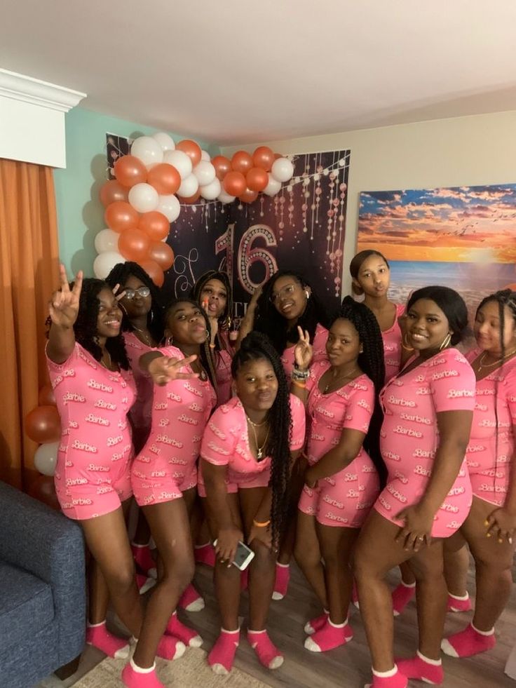 a group of women in pink outfits posing for a photo with balloons and decorations behind them