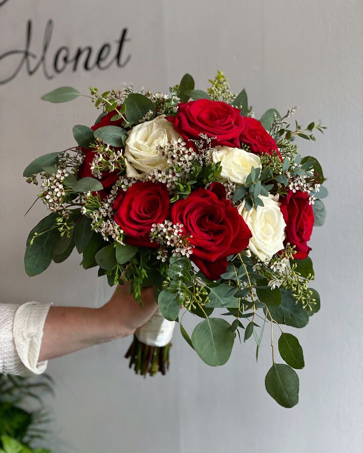 a person holding a bouquet of red and white roses