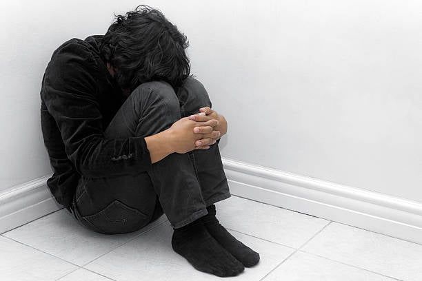 a man sitting on the floor with his head in his hands