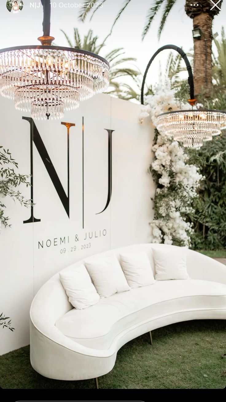 a white couch sitting in front of a wall with chandeliers hanging from it