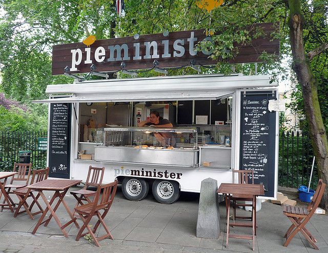 a food truck parked on the side of a road with tables and chairs around it