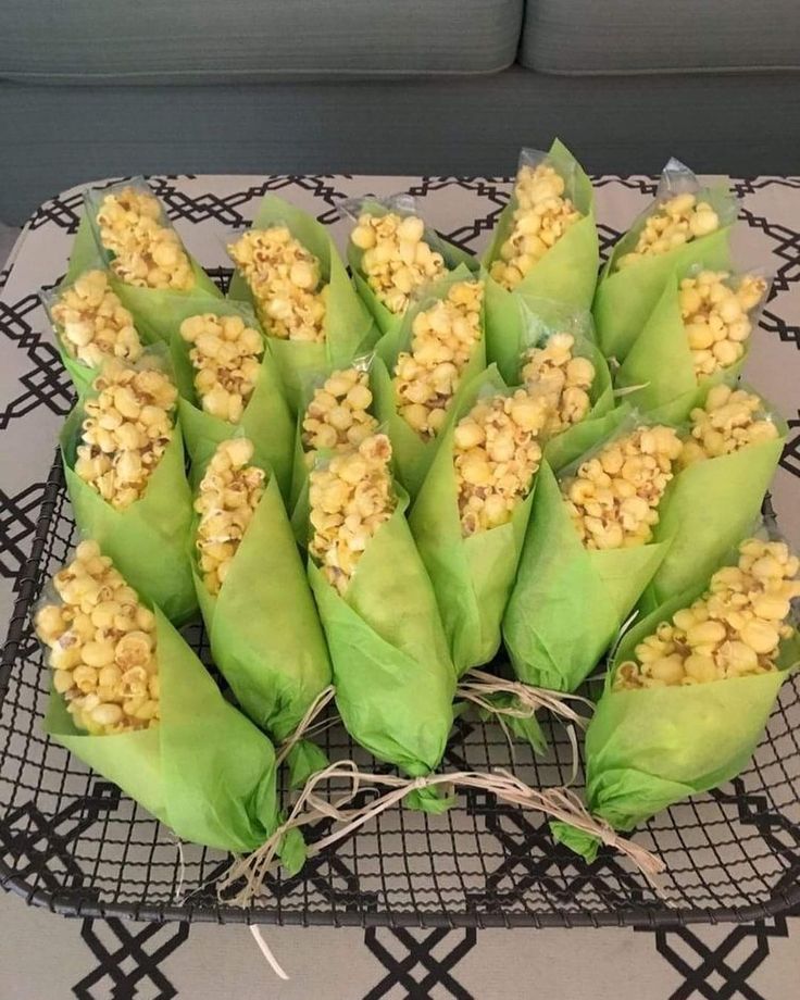 corn on the cob wrapped in paper sitting on top of a black wire tray