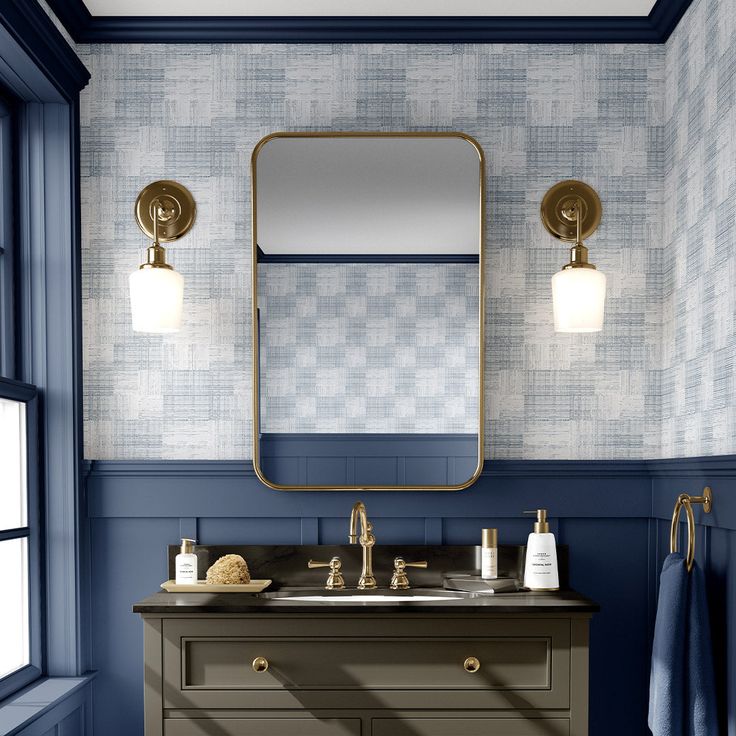 a bathroom with blue and white walls, gold fixtures and a large mirror on the wall