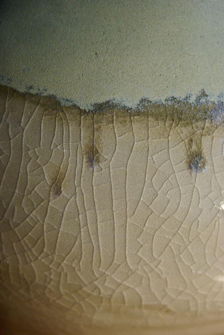 the bottom part of a vase with water and sand on it's sides, in front of a wall