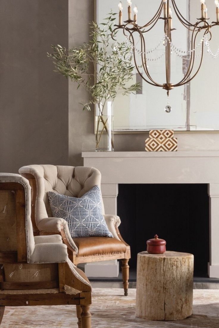 a living room filled with furniture and a chandelier hanging from the ceiling over a fire place