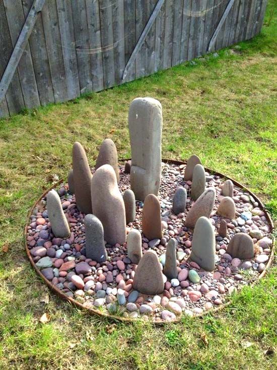 a rock garden in the middle of a yard with rocks and gravel around it,