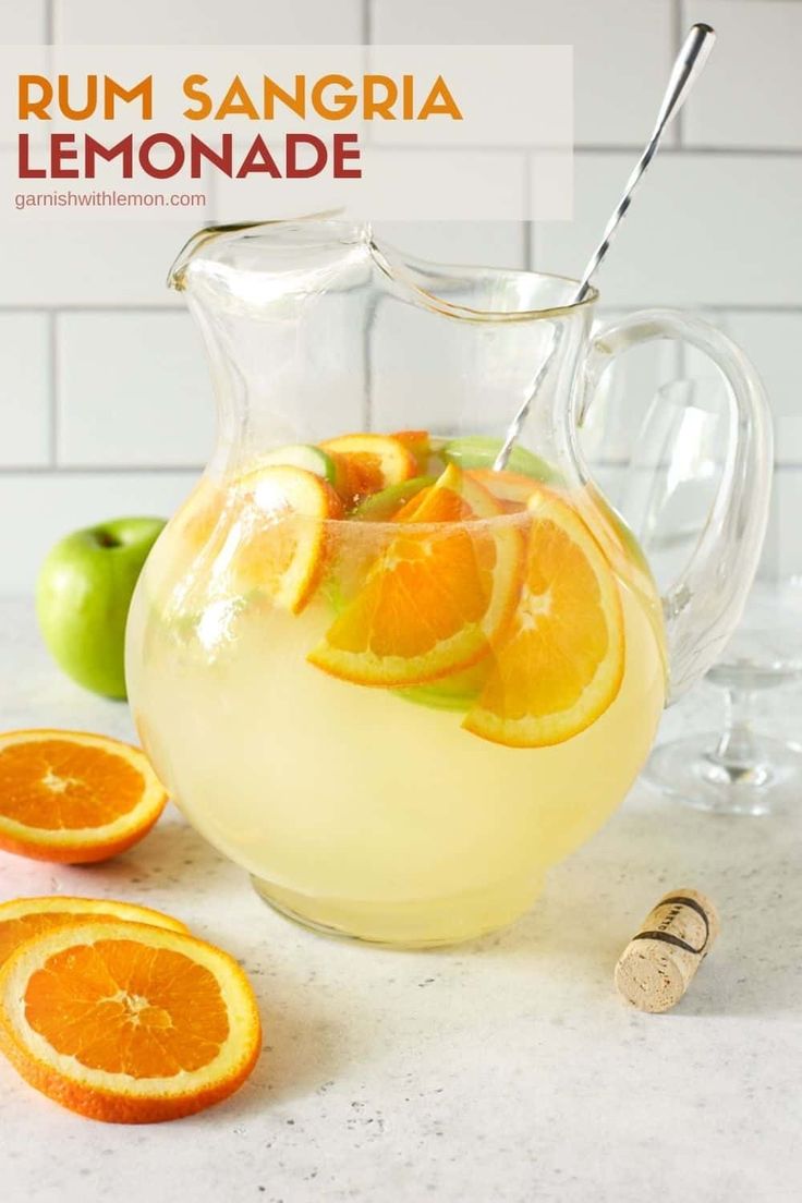 a pitcher filled with lemonade next to sliced oranges