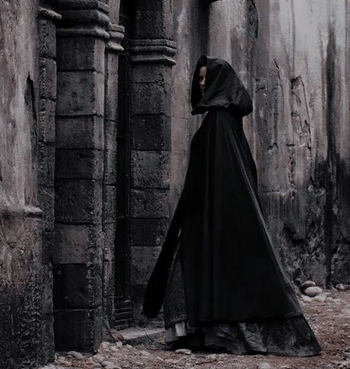 black and white photograph of a nun standing in an alleyway with her back to the camera