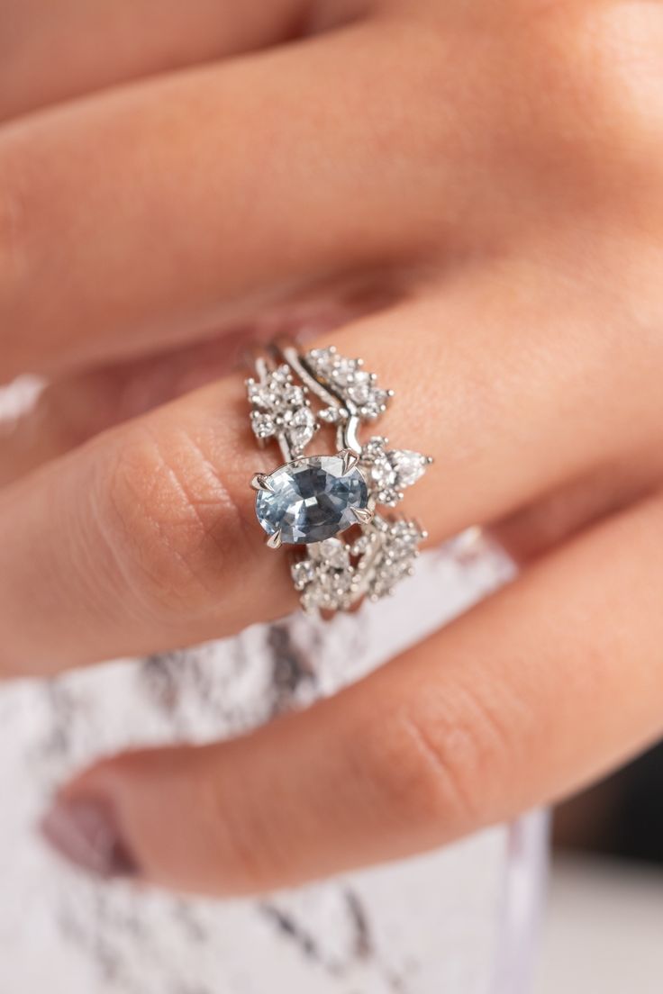 a woman's hand wearing a ring with blue and white stones on it,